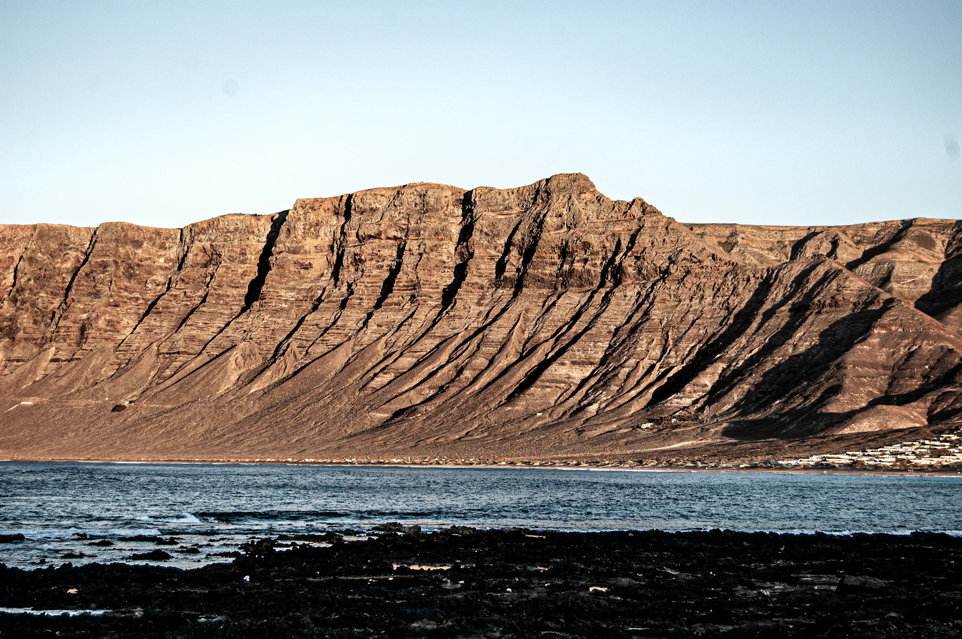 Layered volcanic rock formation with black lava foreground on the Lanzarote coastline